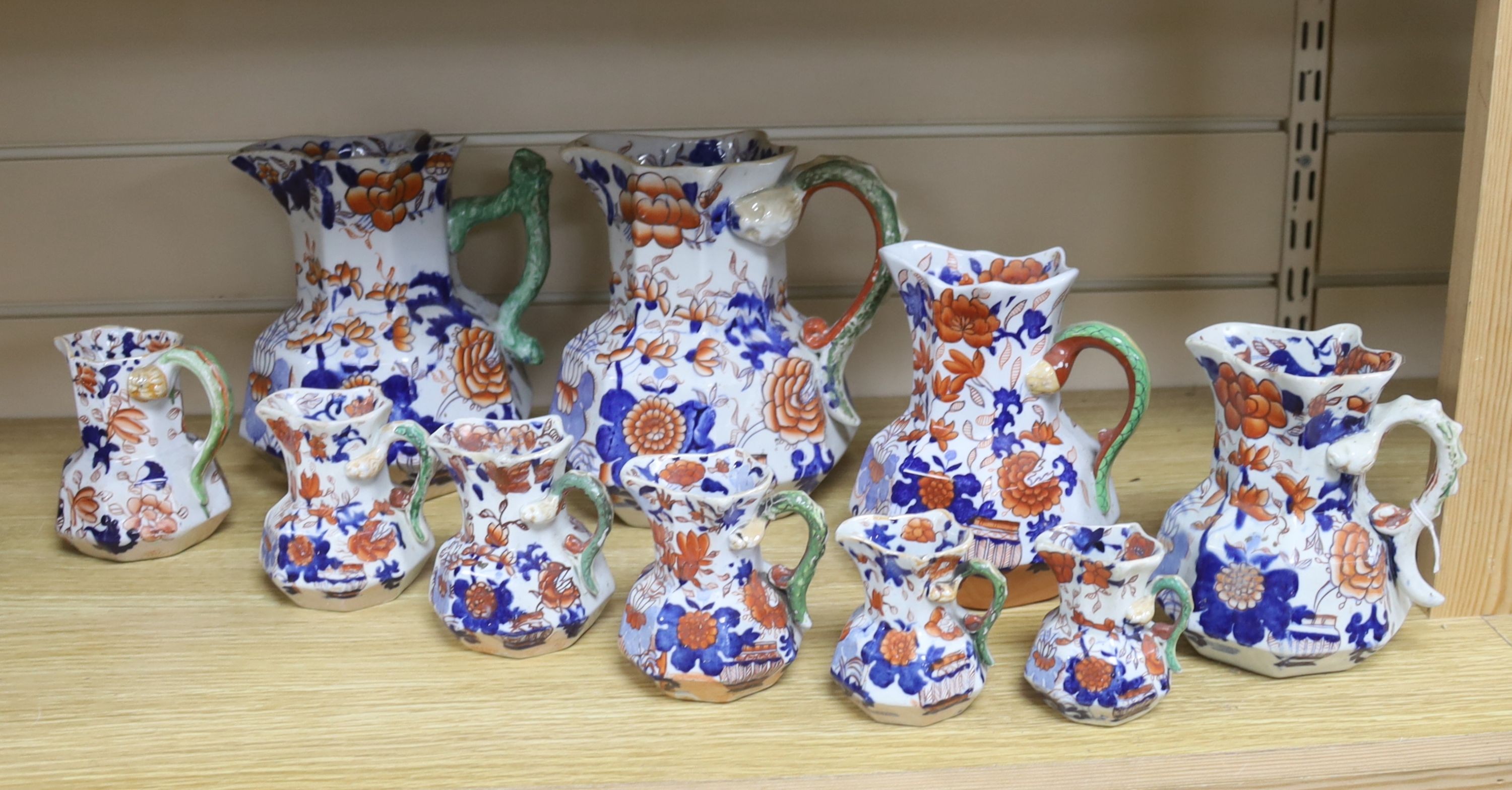 A graduated set of eight Mason's floral Imari pattern ironstone hydra jugs, c.1820-30, largest 19cm smallest 7cm and two other Mason’s ironstone jugs (10)